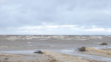 Kumlu sahilde dalgalar deniz. Bulutlu gökyüzü gri su ile deniz manzarası. Doğanın gücünü. Yolculuk tutkusu veya seyahat ve tatil. Video
