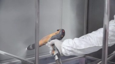 El boyama boya tabancası tarafından bir metal yüzey. Küçük. Koruyucu elbiseli adam fabrika boyalar