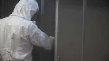 Toz boya metal parçalar. Küçük. Koruyucu elbiseli bir adam bir silahtan toz boya metal ürünlerde spreyler