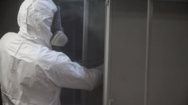 Toz boya metal parçalar. Küçük. Koruyucu elbiseli bir adam bir silahtan toz boya metal ürünlerde spreyler