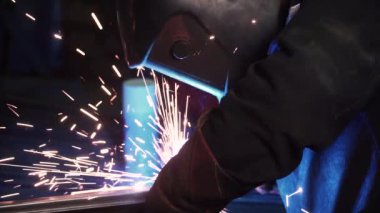 Bir adam bir kaynak makinesi ile çalışır. Küçük. Fabrikada kaynak çelik yapılar. Dışarı güzel kıvılcımlar