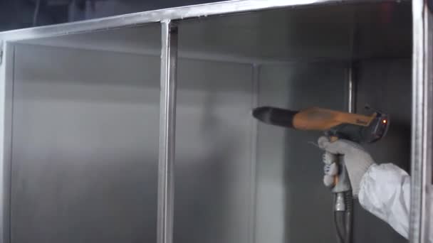 Hand painting of a metal surface by spray gun. Clip. Man in a protective suit paints the factory — Stock Video