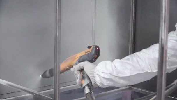 Schilderij van de hand van een metalen oppervlak door spuitpistool. Clip. Man in een beschermend pak schildert de fabriek — Stockvideo