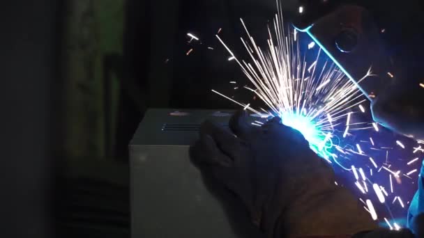 Un hombre trabaja con una máquina de soldadura. Clip. Soldadura de estructuras de acero en la fábrica. Hermosas chispas vuelan — Vídeo de stock