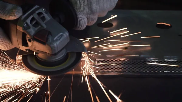 O homem esmaga uma folha de metal. Clipe. Máquina de moagem no trabalho e movimento de faísca na indústria de peças automotivas — Fotografia de Stock