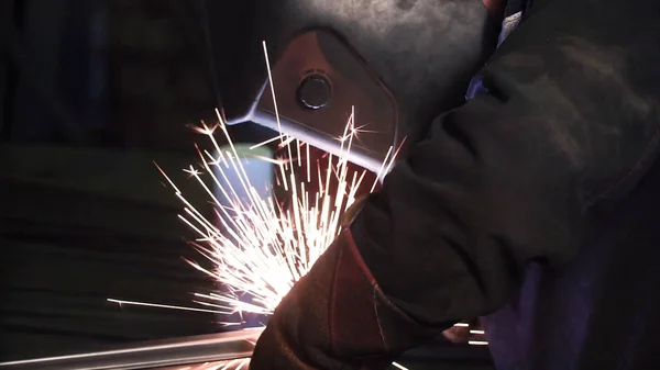 Seorang pria bekerja dengan mesin las. Jepit. Struktur baja pengelasan di pabrik. Indah bunga api terbang keluar — Stok Foto