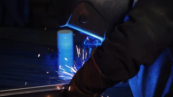 A man works with a welding machine. Clip. Welding steel structures in the factory. Beautiful sparks fly out
