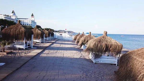 Вид с воздуха на волны, песчаный пляж с тростниковыми зонтиками. Видео. Вид сверху на песчаный пляж с естественными пумбрелами — стоковое фото