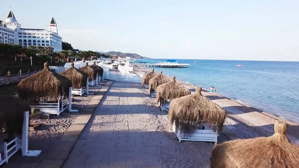 Вид с воздуха на волны, песчаный пляж с тростниковыми зонтиками. Видео. Вид сверху на песчаный пляж с естественными пумбрелами — стоковое фото