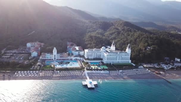 Vista superior de las casas en la playa de palmeras, piscina y barco cerca de un muelle de madera. Vídeo. Vista superior del resort de lujo en la playa — Vídeo de stock