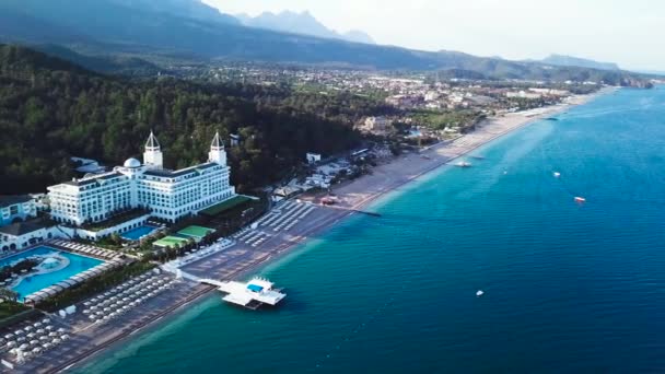 Vista superior de las casas en la playa de palmeras, piscina y barco cerca de un muelle de madera. Vídeo. Vista superior del resort de lujo en la playa — Vídeo de stock