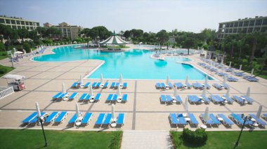 Güneşli bir yüzme havuzu. Video. Tropik bahçeler, otel sundeck ve havuz manzarası