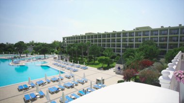 Güneşli bir yüzme havuzu. Video. Tropik bahçeler, otel sundeck ve havuz manzarası