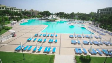 Güneşli bir yüzme havuzu. Video. Tropik bahçeler, otel sundeck ve havuz manzarası