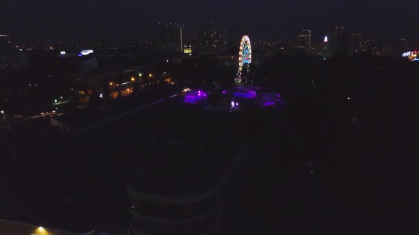 Rueda de la fortuna en un parque de la ciudad por la noche. Clip. Vista superior de la brillante noria por la noche — Vídeo de stock