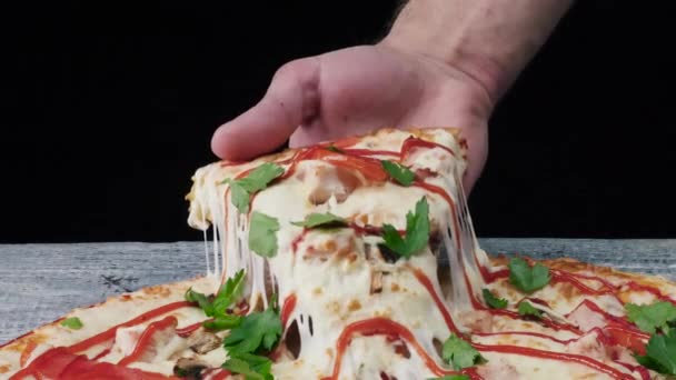 Man tar en bit av pizza med handen. Ram. Manlig hand tar bit pizza med stretchig ost — Stockvideo