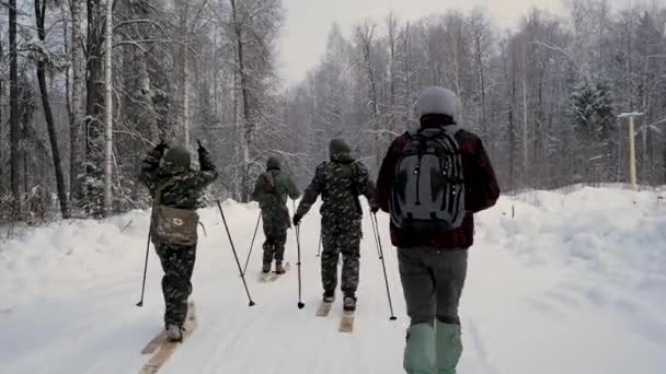 Group of soldiers run on skis in the woods with weapons. Clip. Soldiers with AK-47 rifles and grenade launchers running through the winter forest on skis. Soldiers on exercises in the woods in winter — Stock Video