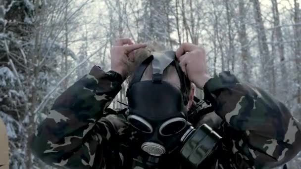 Hombre de uniforme con una máscara de gas en el bosque de invierno. retrato de un joven soldado con una máscara de gas sobre un fondo natural . — Vídeo de stock