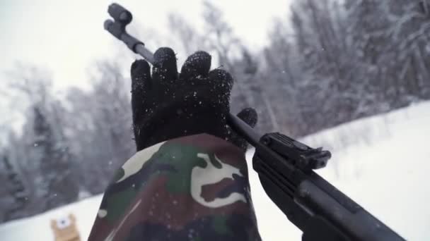 Un hombre apuntando una pistola de perdigones hacia un objetivo, practicando su puntería en invierno. Clip. El tirador en camuflaje apunta a un objetivo con un rifle con una vista óptica, se centran en las armas . — Vídeos de Stock