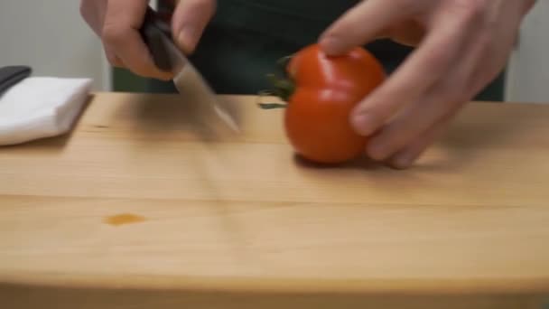 반으로 슬라이스 토마토입니다. 클립입니다. 요리, 음식, 가정 개념-절단 보드 집에서 남성의 손 절단 고추의 닫습니다. 남성 손 절단 토마토의 클로즈업 — 비디오