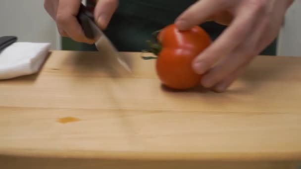 Trancher les tomates en deux. Clip. cuisine, nourriture et concept maison - gros plan du poivre masculin coupé à la main sur la planche à découper à la maison. gros plan de tomates coupées à la main mâles — Video