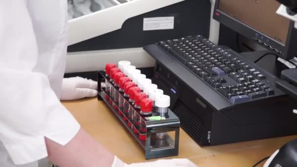 Investigadora médica o científica que usa tubos de ensayo en laboratorio. Clip. Female Scientist Analyses Liquid in the Beaker and Types Down Observations on Her Computer (en inglés). Trabaja en un laboratorio — Vídeo de stock