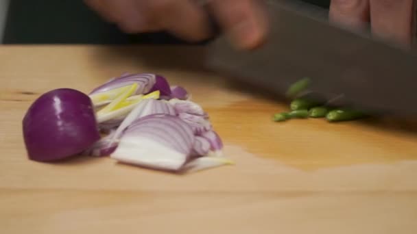 Male hands with knife, cutting fresh onion. Clip. Meal cutting on a wooden board close up. Male hands using a knife cut a fresh red onion on a cutting board. Close-up — Stock Video