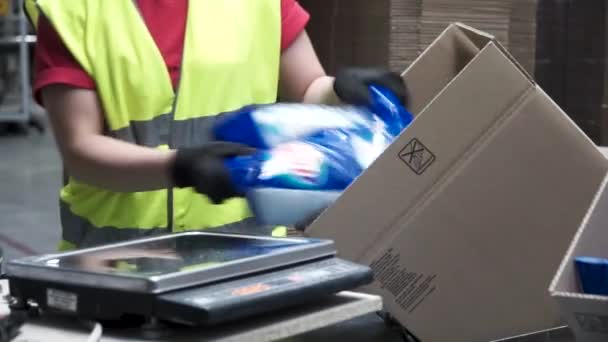 Närbild av händerna på en fabriks arbetare att sätta förpackade produkter i kartong, före export eller transport under manuellt arbete i en fabrik i kosmetika. Klipp. Arbetstagare på lagerställe — Stockvideo