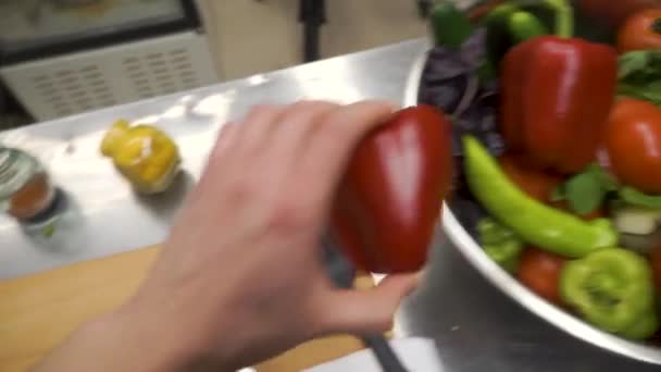 Knife cuts red bell pepper on wooden cutting board. Clip. Cutting core in sweet pepper on wooden cutting board. Remove seeds from red sweet pepper with knife. Preparation of vegetables. Top view. The — Stock Video