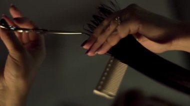 Profesyonel kuaför salon, istemci ile çalışma kapatın. Çerçeve. Salonların bir close-up karanlık bir arka plan ile kırmızı saç kesimini eller. Saç Bakımı, sağlık kavramı