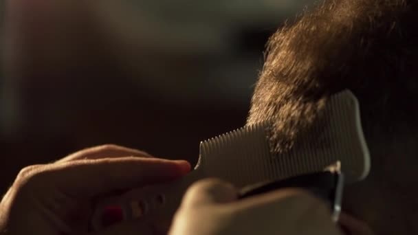 Peluquero con peine y clipper haciendo su trabajo. Una trampa. Un hombre con un corte de pelo con una cortadora de pelo. Primer plano de hombre consiguiendo corte de pelo de moda en la peluquería . — Vídeos de Stock