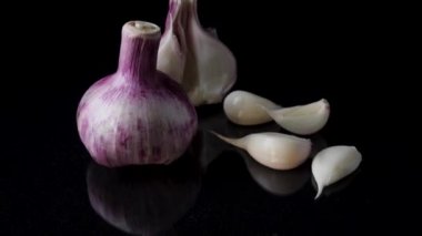 Siyah arka planda soğan ve sarımsak. Soğanların durgun yaşamı ve siyah arka planda düşen sarımsak