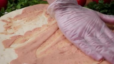 Şef baker mutfak Pizza'da yapma Beyaz üniformalı closeup el. Çerçeve. Pizza yemek. İşlenecek parçanın domates sosu döktü. Şef sprinkles peynirli pizza, bir sürü peynir pişirme işlemi bir pizza