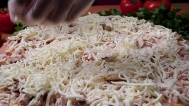 Şef baker mutfak Pizza'da yapma Beyaz üniformalı closeup el. Çerçeve. Pizza yemek. İşlenecek parçanın domates sosu döktü. Şef sprinkles peynirli pizza, bir sürü peynir pişirme işlemi bir pizza
