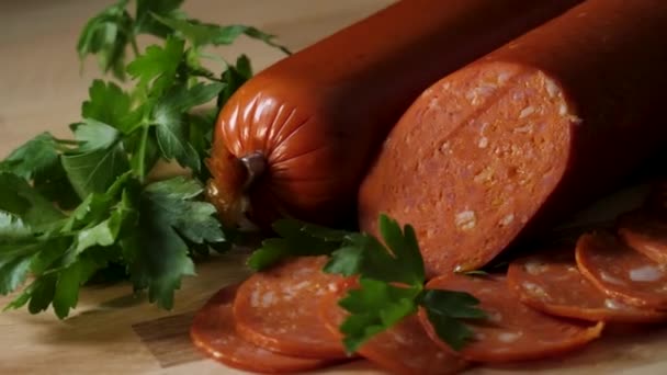 Dried organic salami sausage on wooden cutting board. Frame. Sausage on a wooden board with rosemary and spices. A piece of sausage is pinned on the fork. German meat products. View from above. Rustic — Stock Video