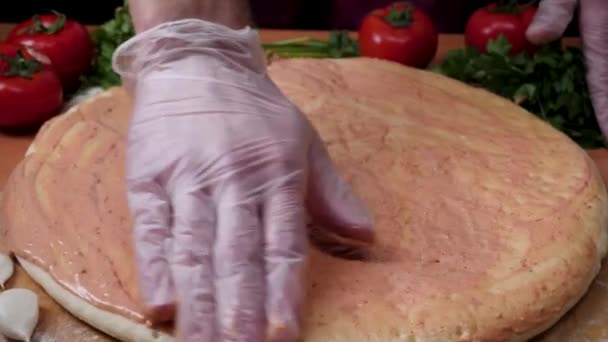 Het toevoegen van saus. Italiaanse pizza bereiding. Frame. Kaas wordt verspreid op de tomatensaus op pizza base. Closeup hand van chef-kok Bakker in witte uniform maken pizza op keuken — Stockvideo