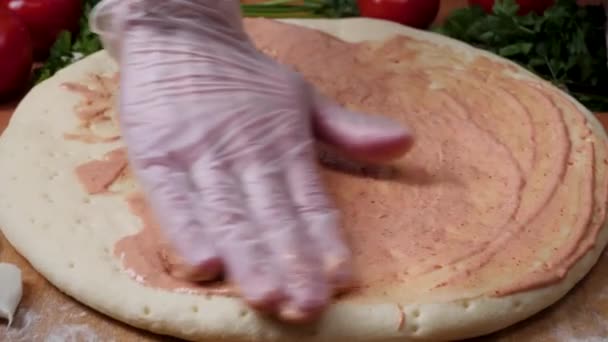 소스를 추가합니다. 이탈리아 피자 준비입니다. 프레임입니다. 치즈 피자 기본에 토마토 소스에 확산 되 고. 흰색 유니폼 주방에서 피자 만드는 요리사 베이커의 근접 촬영 손 — 비디오