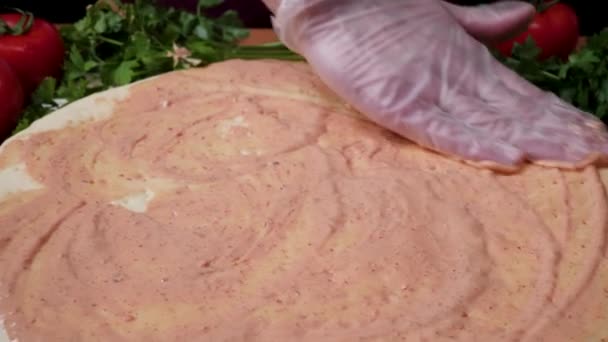 Adding sauce. Italian pizza preparation. Frame. Cheese being spread on tomato sauce on pizza base. Closeup hand of chef baker in white uniform making pizza at kitchen — Stock Video