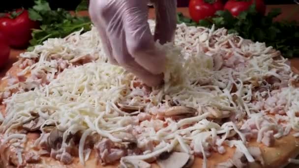 Додавання соусом. Італійська піца приготування. Кадр. Сир поширюється на томатний соус на піца бази. Крупним планом рука Бейкер шеф-кухаря в білий парадний, роблячи піцу на кухні — стокове відео