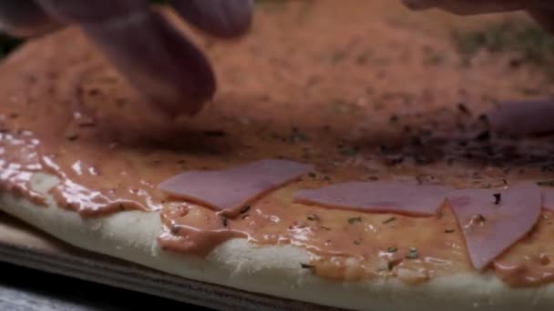 Gătesc pizza încet. Frame. Efectuarea pizza cu brânză, pastă de roșii, cârnați și muștar. Munca bucătarului. Bucătarul aranjează bucăți de cârnați și pizza cu brânză și pastă de roșii. Complet — Videoclip de stoc