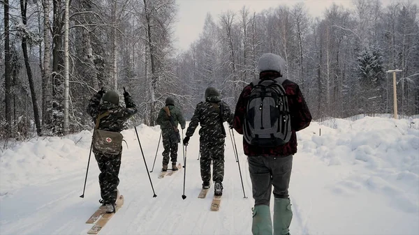 O grupo de soldados corre em esquis na floresta com armas. Clipe. Soldados com fuzis AK-47 e lança-granadas atravessando a floresta de inverno em esquis. Soldados em exercícios na floresta no inverno — Fotografia de Stock