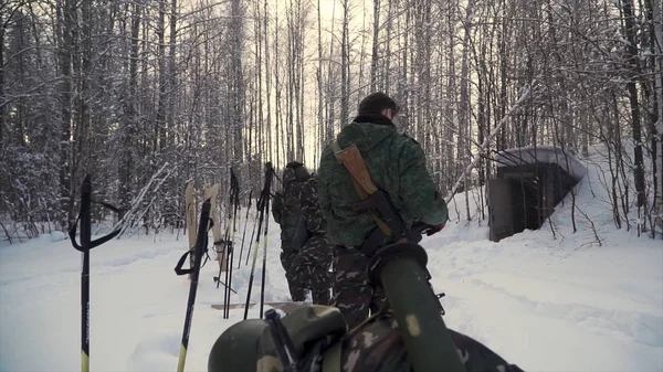 Grupo de soldados corren en esquís en el bosque con armas. Clip. Soldados con rifles AK-47 y lanzagranadas recorriendo el bosque invernal con esquís. Soldados en ejercicios en el bosque en invierno — Foto de Stock