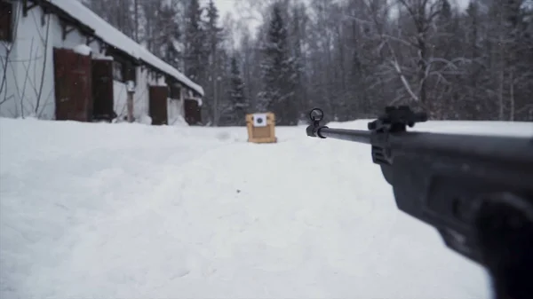 Um homem apontando uma pistola de pellet em direção a um alvo, praticando seu objetivo no inverno. Clipe. O atirador em camuflagem tem como alvo um alvo com uma espingarda com visão óptica, focado em armas . — Fotografia de Stock