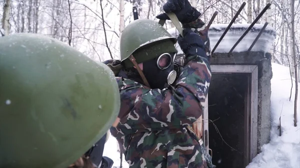 Man in uniform dragen een gasmasker in het forest van de winter. Portret van een jonge soldaat het dragen van een gasmasker tegen een achtergrond van de natuur. — Stockfoto