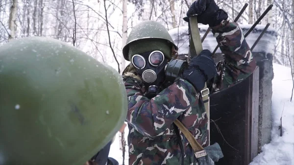 Чоловік у формі в газовій масці в зимовому лісі. портрет молодого солдата в газовій масці на фоні природи . — стокове фото