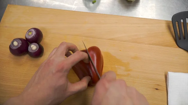 Il coltello taglia il peperone rosso sul tagliere in legno. Clip. Nucleo di taglio in peperone dolce su tagliere di legno. Tolga semi da dolce pepe rosso con coltello. Preparazione di verdure. Vista dall'alto. Il — Foto Stock