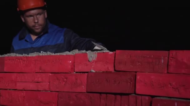 Homem em equipamento de trabalho constrói uma parede de tijolo. Estoque. Conceito de autodesenvolvimento. Construir uma carreira, para si mesmo, para a vida — Vídeo de Stock