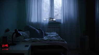 Bir adam derin depresyon gece manzarası. Yalnız adam karanlıkta yatakta yatan