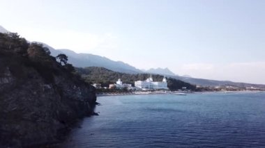 Video. Otelin deniz ve dağlar havadan görünümü ile yeşil orman, blue sky adlı gündoğumu ağaçlarıyla kaplı. Video. Lüks Otel ile orman ve dağlar bir arka plan ile sahil üzerinde havadan görünümü