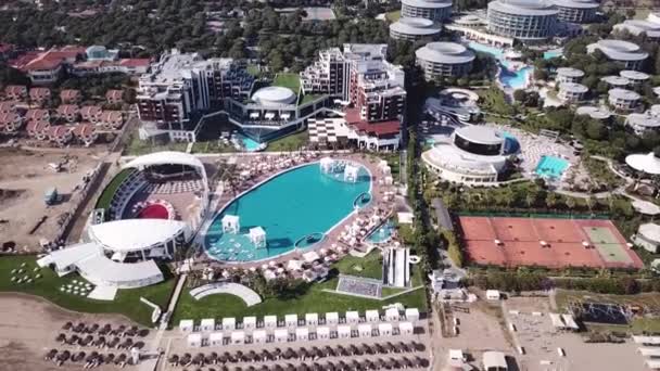 Hotel aan het zwembad met ligstoelen en palmbomen. Clip. Bovenaanzicht geschoten. Zwembad omliggende palmen en groene tuin in het prachtige tropische resort, luchtfoto bovenaanzicht — Stockvideo